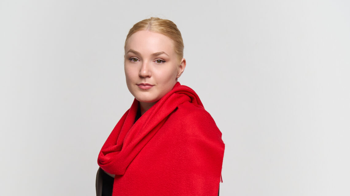 A model styled in a charcoal and red cashmere scarf, representing the brand's global appeal.